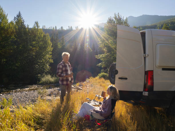 istock Mature couple relax with drinks beside campervan 1648524377