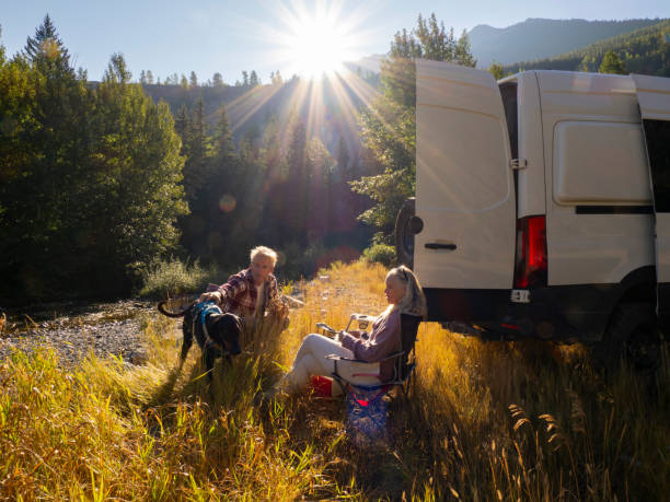 istock Mature couple relax with drinks beside campervan 1648524389