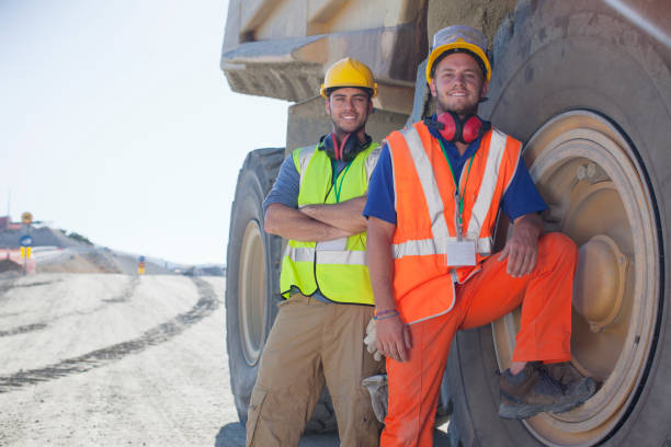 travailleurs s'appuyant sur des machines sur place - construction safety mid adult men road construction photos et images de collection