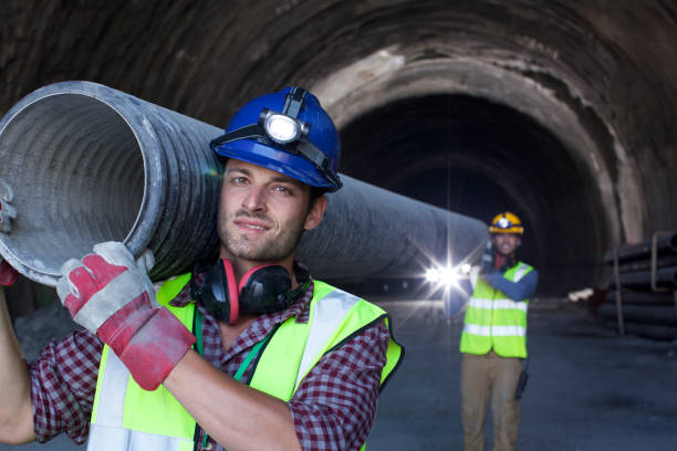 los trabajadores llevar largo de tubo en túnel - faro estructura de edificio fotografías e imágenes de stock