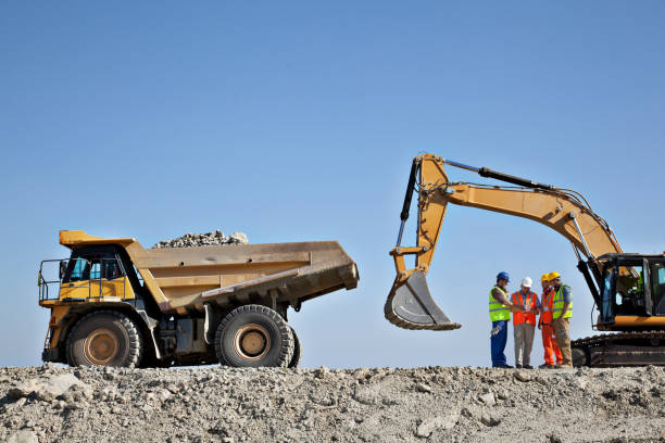 Workers talking by machinery in quarry stock photo
