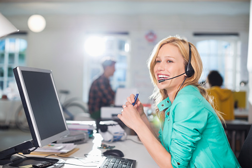 Young woman talking with her coworker while working on the call center at office