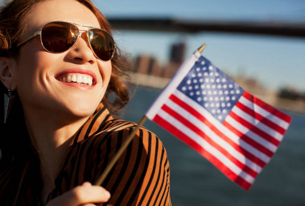 Woman waving American flag by urban bridge stock photo