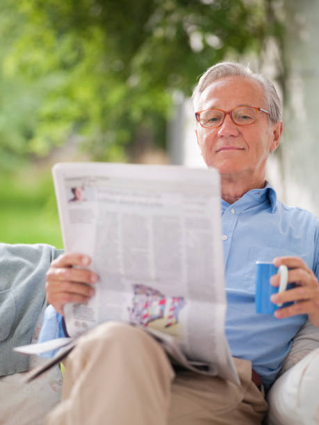 istock Man reading newspaper in porch swing 164853508