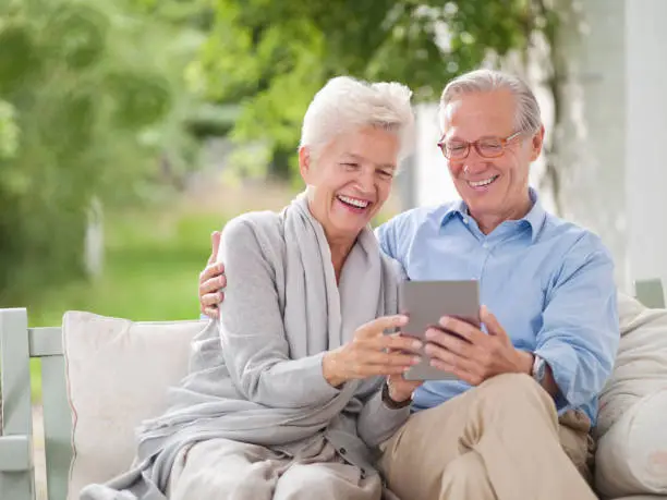 Photo of Couple using digital tablet together on porch swing