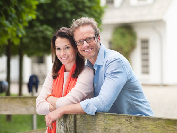 Couple smiling by wooden fence  mid adult couple stock pictures, royalty-free photos & images