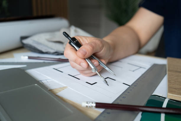 istock Female architect or interior designer with compass tool, working on home floor plans and structural blueprints at a studio desk. 1648544891