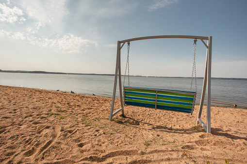Swing on a sandy beach with fine sand by the lake on a sunny day