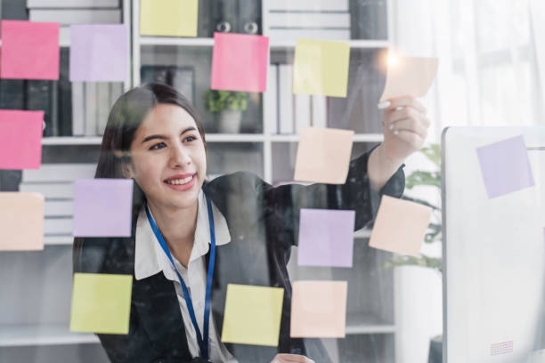 istock Young businesswoman creative team using post it notes in glass wall to writing strategy business plan to development grow to success. 1648565136