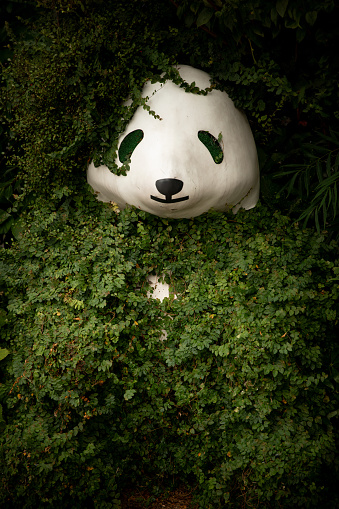 Abandoned panda statue covered by vegetation