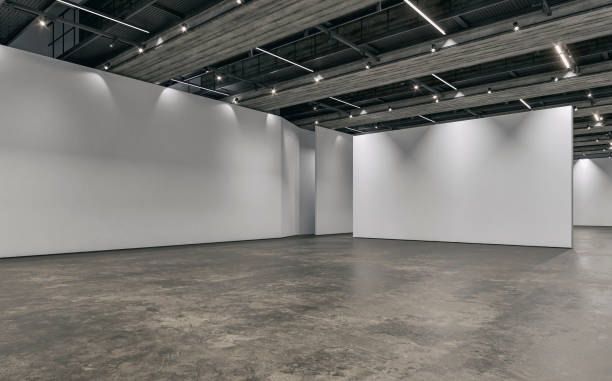 Side view of an empty white large gallery/showroom interior with white partition empty walls for events or artwork exposure, and a ceiling industrial construction with reflectors (lights) stock photo