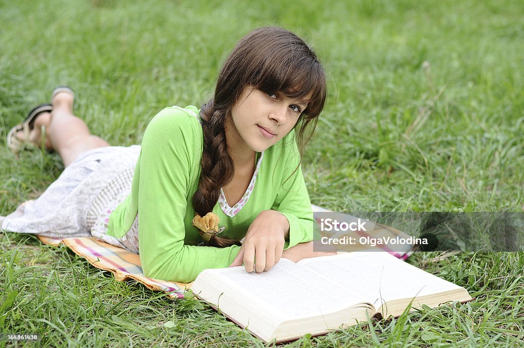 Fille lisant un livre allongé sur l'herbe - Photo de 16-17 ans libre de droits