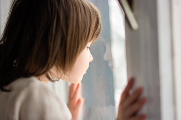 istock Cute girl looking through window at home 1648624181