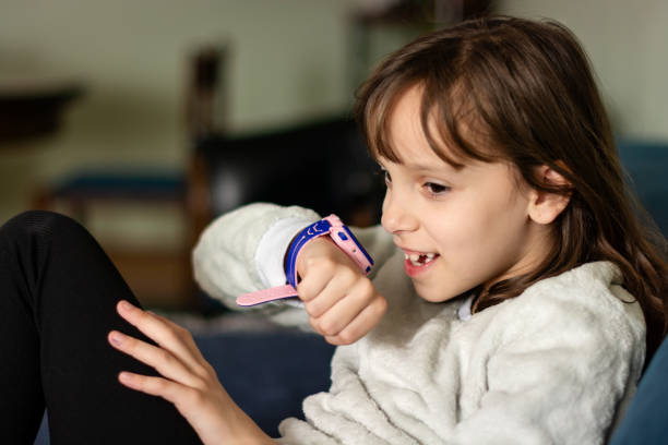 istock Little girl using smart watch while sitting on sofa in living room 1648627339