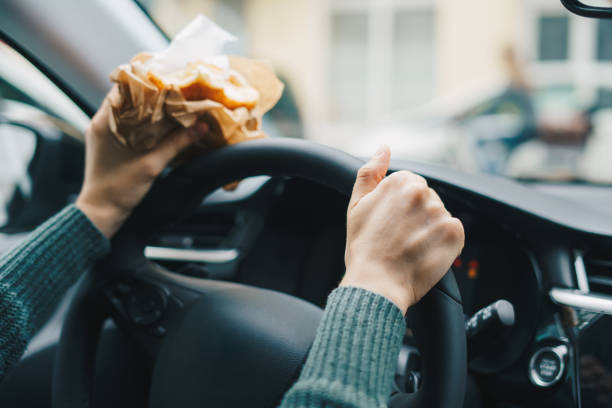 istock Woman eating while driving a car. Distracted driving concept. 1648634231