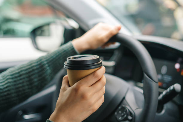 Woman drinking coffee while driving a car