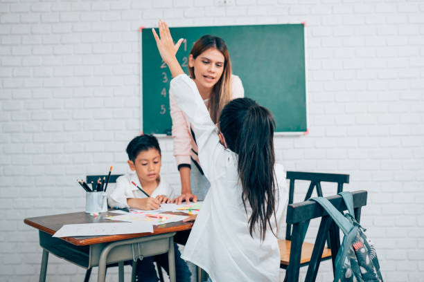 istock Little children raising hands up and having fun in class. 1648651050