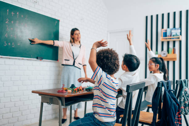 istock Little children raising hands up and having fun in class. 1648659660