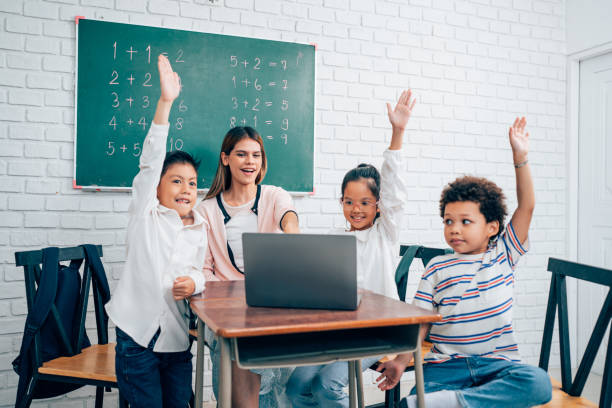 istock Little children raising hands up and having fun in class. 1648666357