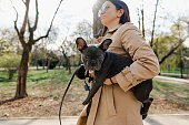 Young woman with her french bulldog puppy on a walk in the park