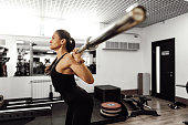 Fit woman doing squats with barbell in a gym
