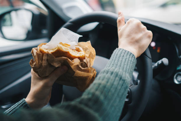 istock Woman eating while driving a car. Distracted driving concept. 1648678684