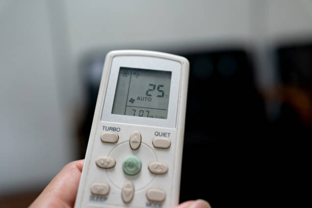 istock Modern air conditioner unit with a hand holding a remote. 1648679799