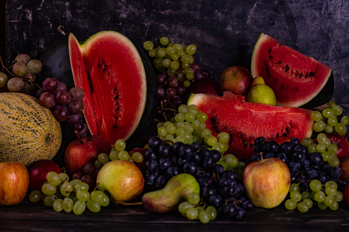 Still life of watermelon and fruit on black background, composition for Harvest Festival or Thanksgiving Day, copy space, place for text