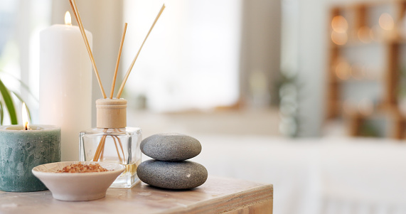 Spa, rock and candle to relax in a room with atmosphere, mood or ambience in a health club. Wellness, luxury and treatment with still life objects on a table in a clinic for rest and relaxation