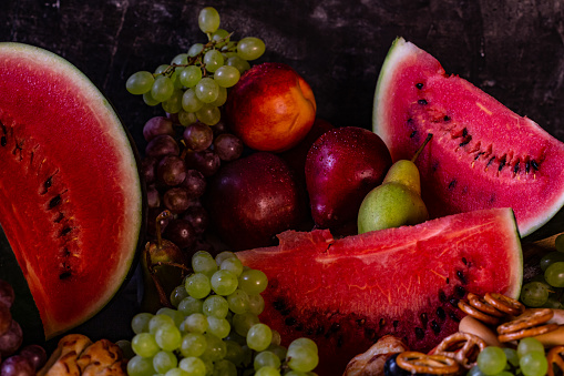 Still life of watermelon and fruit on black background, composition for Harvest Festival or Thanksgiving Day, copy space, place for text