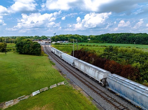 Aerial view of a long freight train traveling through the scenic countryside of Delaware on a sunny day