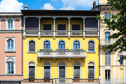 three white windows with sandstone sills in a row with dark blue shutters and a house wall painted orange yellow