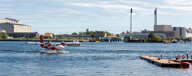 Small modern propeller business charter seaplane landing at Copenhagen water harbour. Sea plane aerial view city sightseeing tour. Cityscape scandinavian Denmark city landmark travel trip.