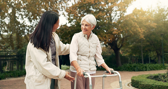 Park, walker and woman help senior walking as support, trust and care for morning healthcare exercise or workout. Health, physical therapy and elderly with caregiver for outdoor rehabilitation