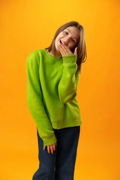Teen girl over yellow background in studio shocked covering mouth with hands
