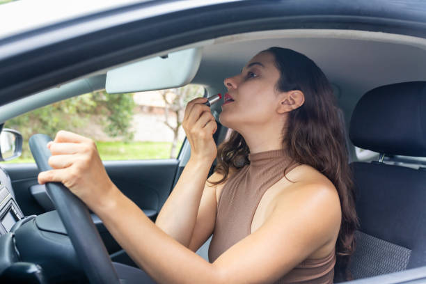 istock Distracted woman painting her lips while driving 1648727478