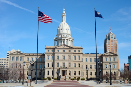 State Capitol Building of Michigan in Lansing with US and Michigan flags.
