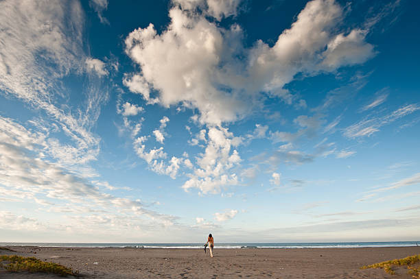 This is a wide angle shot of a woman walking towards the ocean on a breathtaking beach.