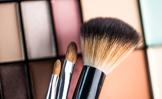 Set of makeup brushes on eyeshadow palette background