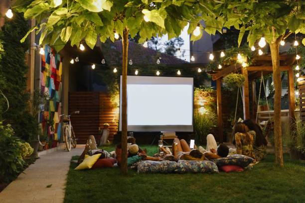 istock Group of people watching a movie on a projection screen in the backyard 1648767754