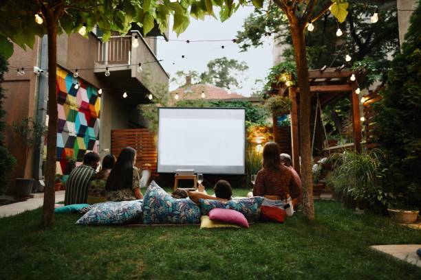 istock Joyful friends watching movies on a projection screen 1648770908