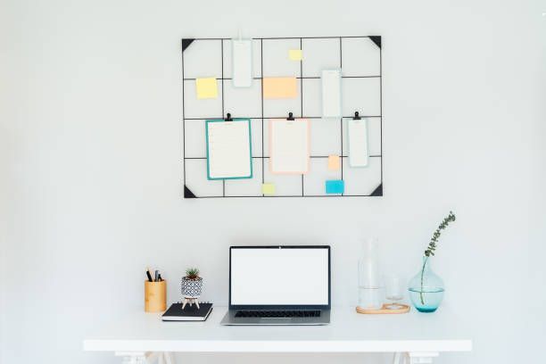 istock Modern workplace - white desk with laptop mockup empty screen, grid mood board with pinned notes and check lists for plans, office supplies at work space in home office room interior. 1648794309