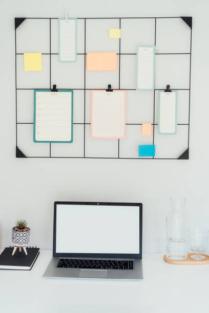 istock Modern workplace - white desk with laptop mockup empty screen, grid mood board with pinned notes and check lists for plans, office supplies at work space in home office room interior. Vertical card. 1648794833