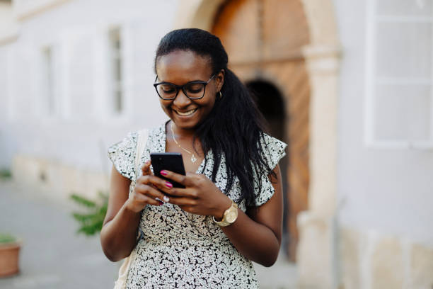 istock Smiling woman using phone on the street 1648795416