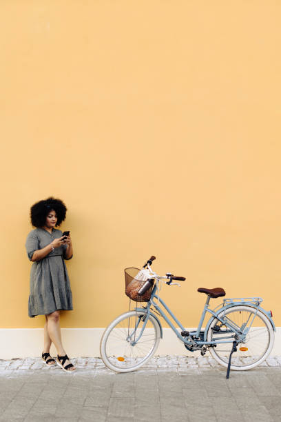 istock Woman using her smart phone while standing near her bicycle 1648795935