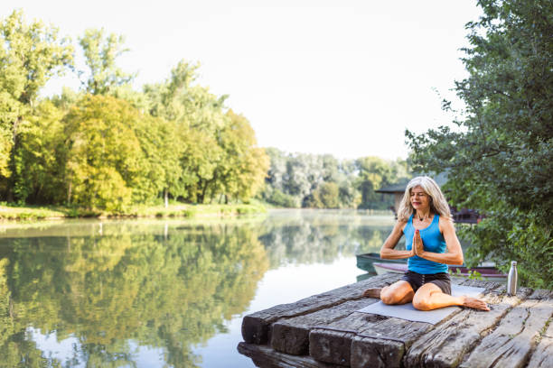 istock Senior woman practicing yoga lake side 1648801334