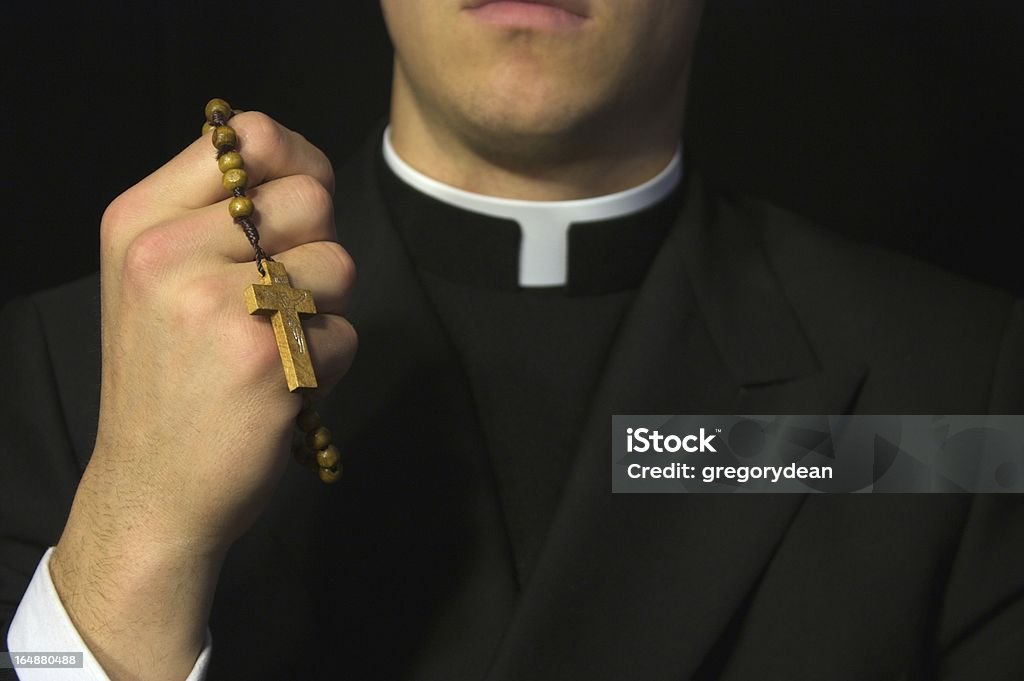 Young Priest praying Young Priest praying with rosery in his hands Priest Stock Photo