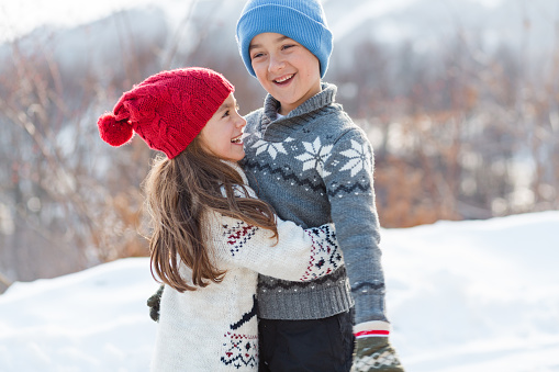 Children having fun walking and embracing ,while walking on the snow in the winter