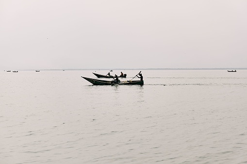 Several fishing boats coast across the surface of Lake Bunyonyi, Uganda