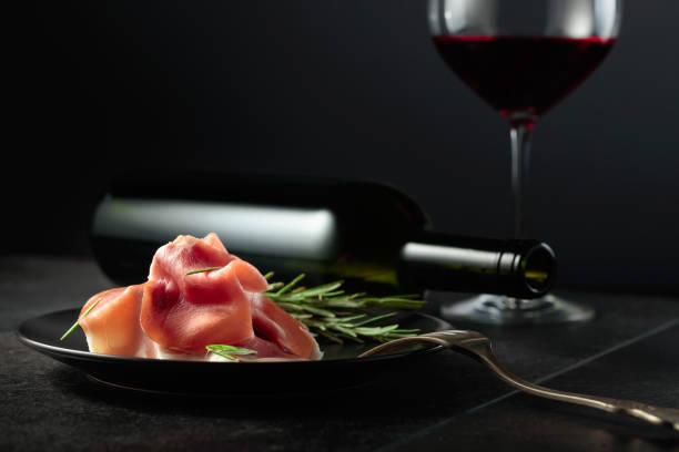 istock Prosciutto with rosemary and red wine on a black background. 1648817051